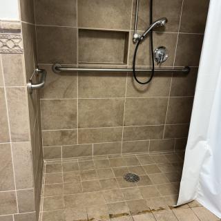 A tiled walk-in shower with a grab bar and handheld showerhead.