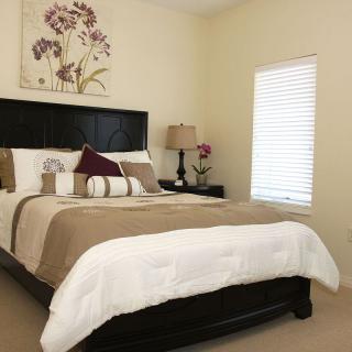 A cozy bedroom with a neatly made bed, soft lighting, and tasteful wall art.