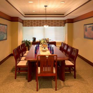 A well-furnished dining room with a long wooden table and chairs, decorated with art and lit by a hanging light fixture.