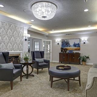 A stylish and elegant living room featuring modern furniture, a decorative wall, and a sparkling chandelier.