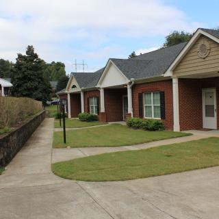 A row of suburban houses with neatly maintained lawns and a sidewalk.