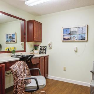 A neatly organized salon interior with a mirror, chair, and wooden cabinets.