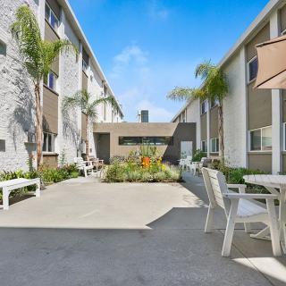 A sunny courtyard in an apartment complex with outdoor seating and palm trees.