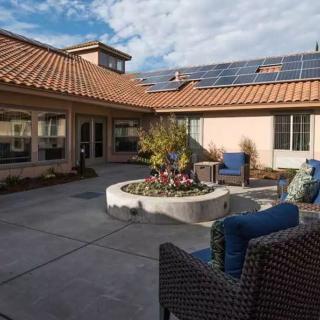 A sunny courtyard patio with seating and solar panels on the roof.