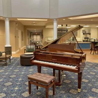 A grand piano in a spacious lobby with seating and columned architecture.