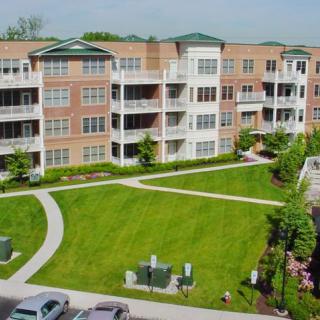 A modern apartment complex with a well-maintained green lawn and landscaped surroundings.