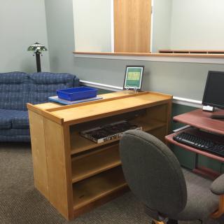 An office space featuring a desk with a computer, a chair, and a blue sofa.
