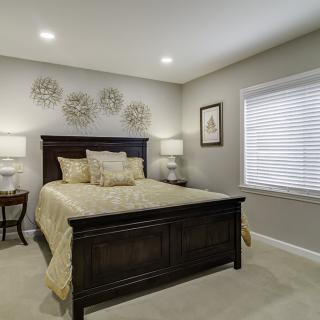 A cozy and elegant bedroom with a dark wooden bed frame, beige bedding, and soft lighting.