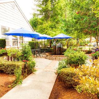 A cozy outdoor patio with blue umbrellas surrounded by lush greenery.