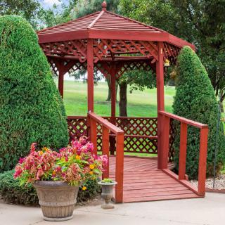 A beautiful wooden gazebo surrounded by lush greenery and vibrant flowers in a garden setting.
