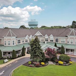 A picturesque view of a large building surrounded by landscaping and greenery under a partly cloudy sky.