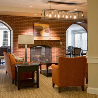 A cozy living room with a fireplace, featuring comfortable seating and a warm brick interior.