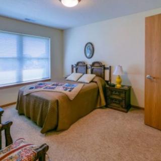 A cozy bedroom with a bed, side table, and a window letting in natural light.