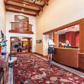 A hotel lobby with a reception desk and an intricate carpet design.
