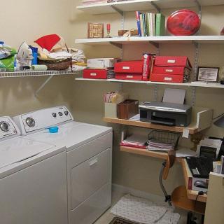 A well-organized laundry room with a washing machine, dryer, and shelving units for storage.