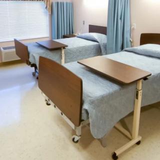 An empty hospital room with two patient beds and privacy curtains.