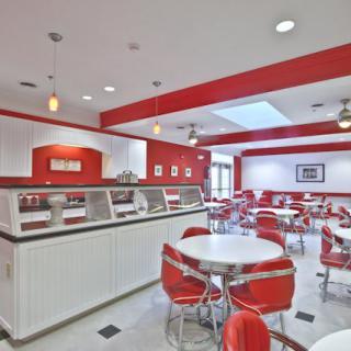 A retro diner interior with red and white decor, featuring round tables and classic seating.
