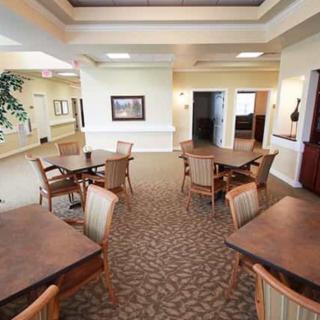 A spacious dining area with multiple tables and chairs arranged on a carpeted floor.