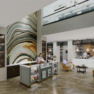 A modern hotel lobby with a reception desk, abstract wall art, and comfortable seating areas.