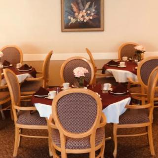 An elegant dining area featuring neatly set tables with comfortable chairs and a framed picture on the wall.