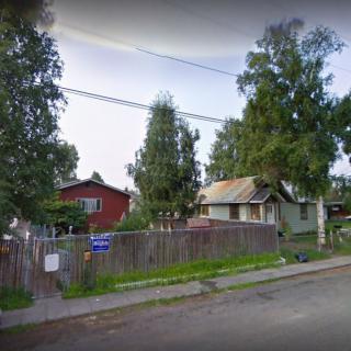 A quiet neighborhood street with houses and trees.