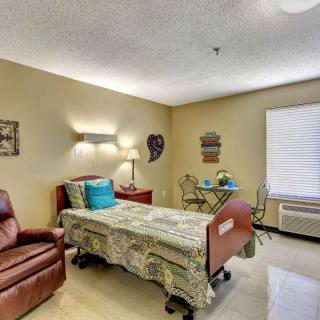 A cozy room featuring a hospital bed, comfortable armchair, and window with natural light.