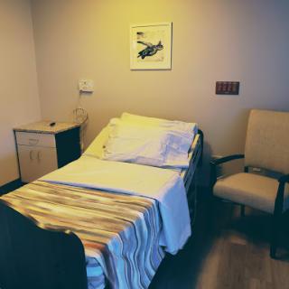 A cozy hospital patient room featuring a bed and chair, designed for comfort and care.