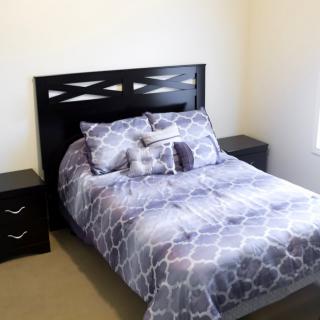 A cozy bedroom with a bed featuring a geometric patterned comforter and matching pillows, flanked by two nightstands.