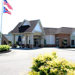 A welcoming entrance to a commercial building, featuring flags and well-manicured landscaping.