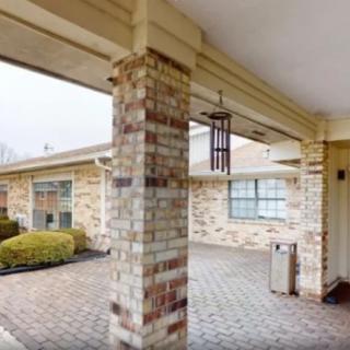 A view of a building's exterior featuring a brick column and a covered walkway.