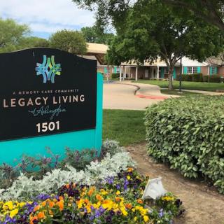 Entrance sign for Legacy Living retirement community surrounded by colorful flowers.
