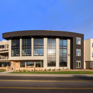 A modern building with a sleek glass facade under a clear blue sky.