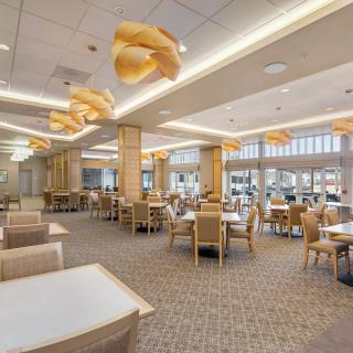 A spacious and modern dining area with stylish overhead lighting and neatly arranged tables and chairs.