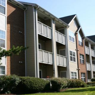 A view of a multi-story apartment building with balconies and well-maintained landscaping.