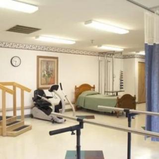 A rehabilitation room equipped with exercise equipment and a bed, designed for physical therapy in a healthcare facility.