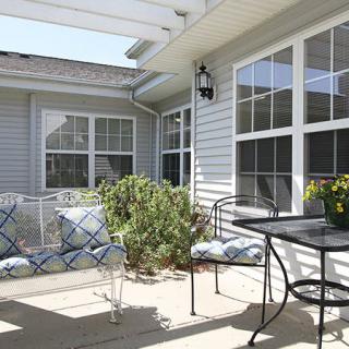 A bright and inviting patio with outdoor seating, plants, and large windows.