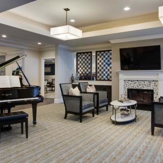 A modern living room with a grand piano, fireplace, and stylish furniture.