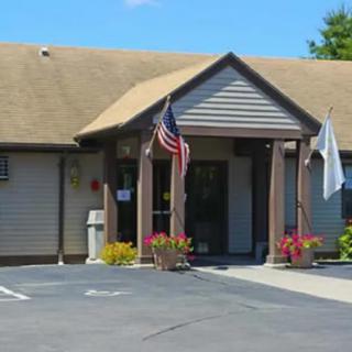 A small building with flags at the entrance and a parking lot in front.