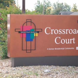 A sign for Crossroad Court, featuring a colorful logo and indicating it is a Superior Redevelopment Corporation property.