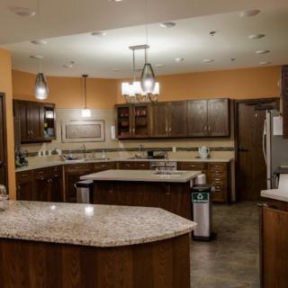 A modern kitchen interior with wooden cabinets, stone countertops, and various appliances.