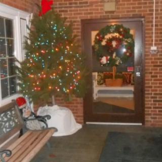 A cozy indoor scene with a decorated Christmas tree and a festive wreath on the door.