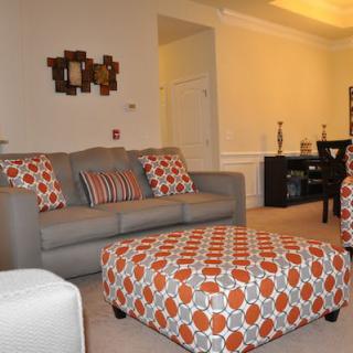 A modern living room with a stylish gray sofa and patterned ottoman.