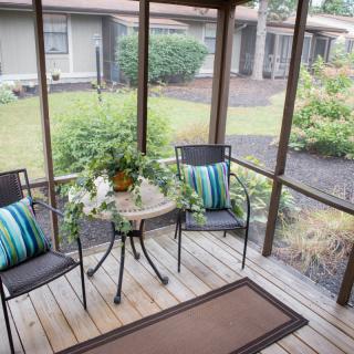 A cozy screened porch with patio furniture and garden view.