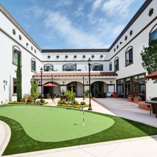 An inviting courtyard with a golf putting green surrounded by a modern building.