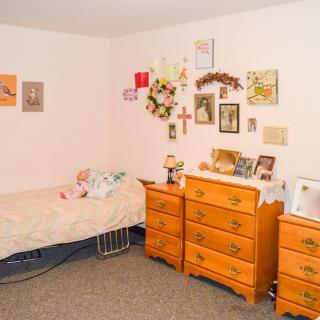 A cozy bedroom with wall decorations and a wooden dresser.