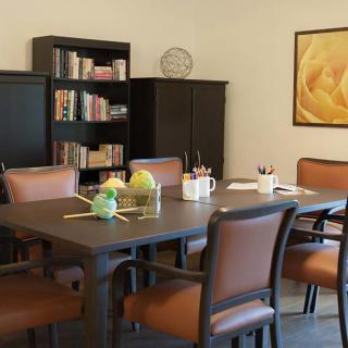 A well-organized meeting room with a conference table, chairs, and a bookshelf filled with books.