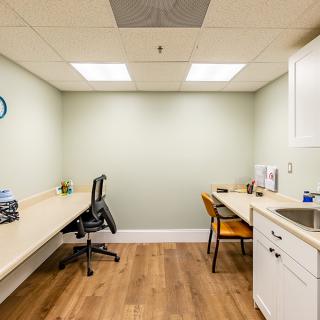 A modern and minimalist office workspace featuring two desks, chairs, and ample lighting.