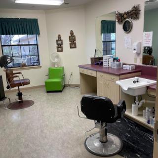 A well-lit and organized salon interior featuring styling chairs, mirrors, and a vibrant green accent chair.