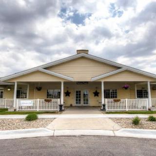 A single-story house with a large porch under a cloudy sky.