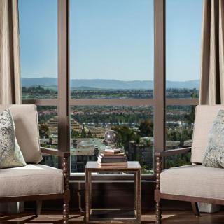 A cozy living space with two chairs overlooking a scenic cityscape through large windows.